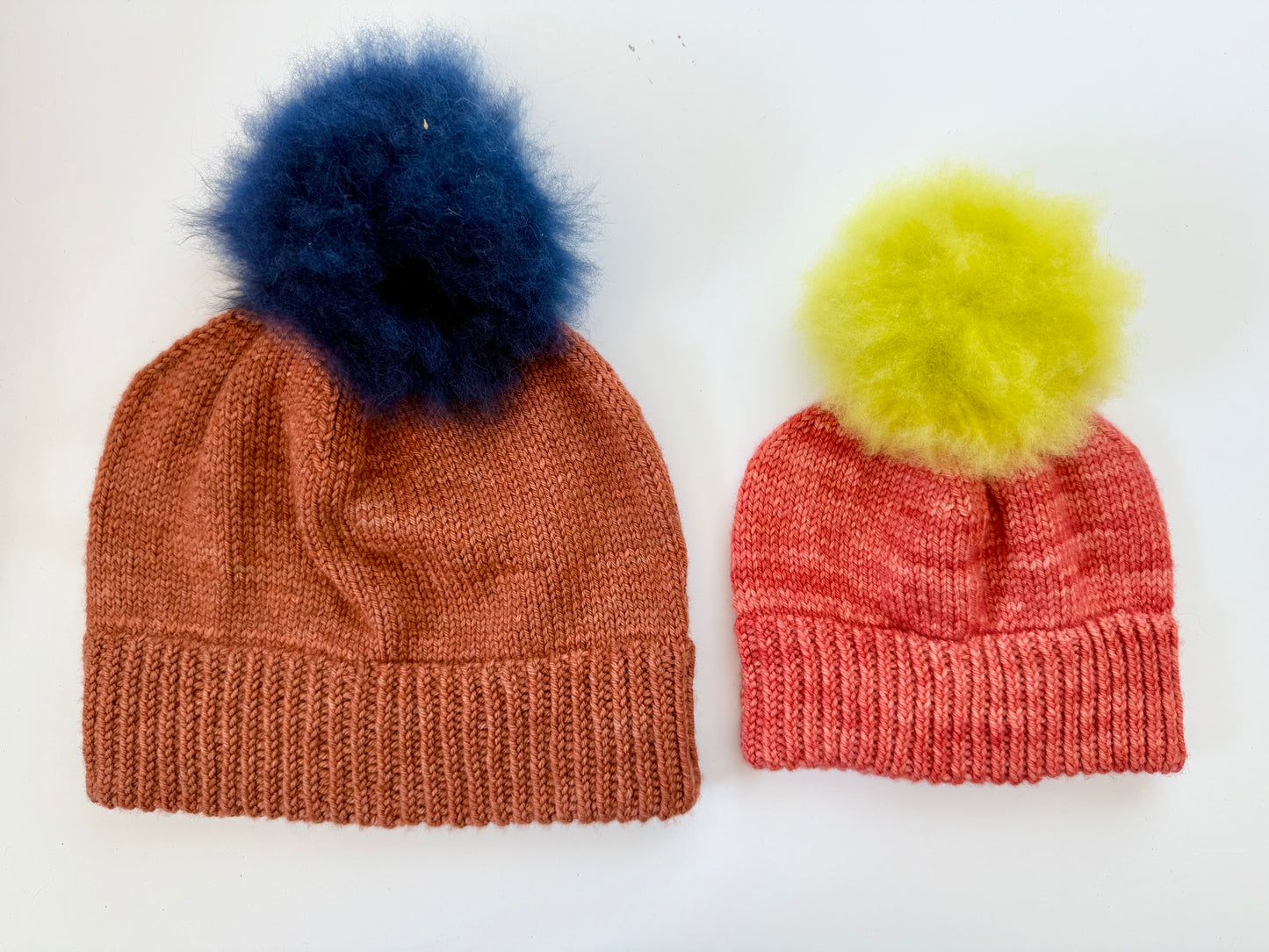 Beanies knit in two sizes from the Doodle beanie base pattern in DK weight yarn with pom poms added