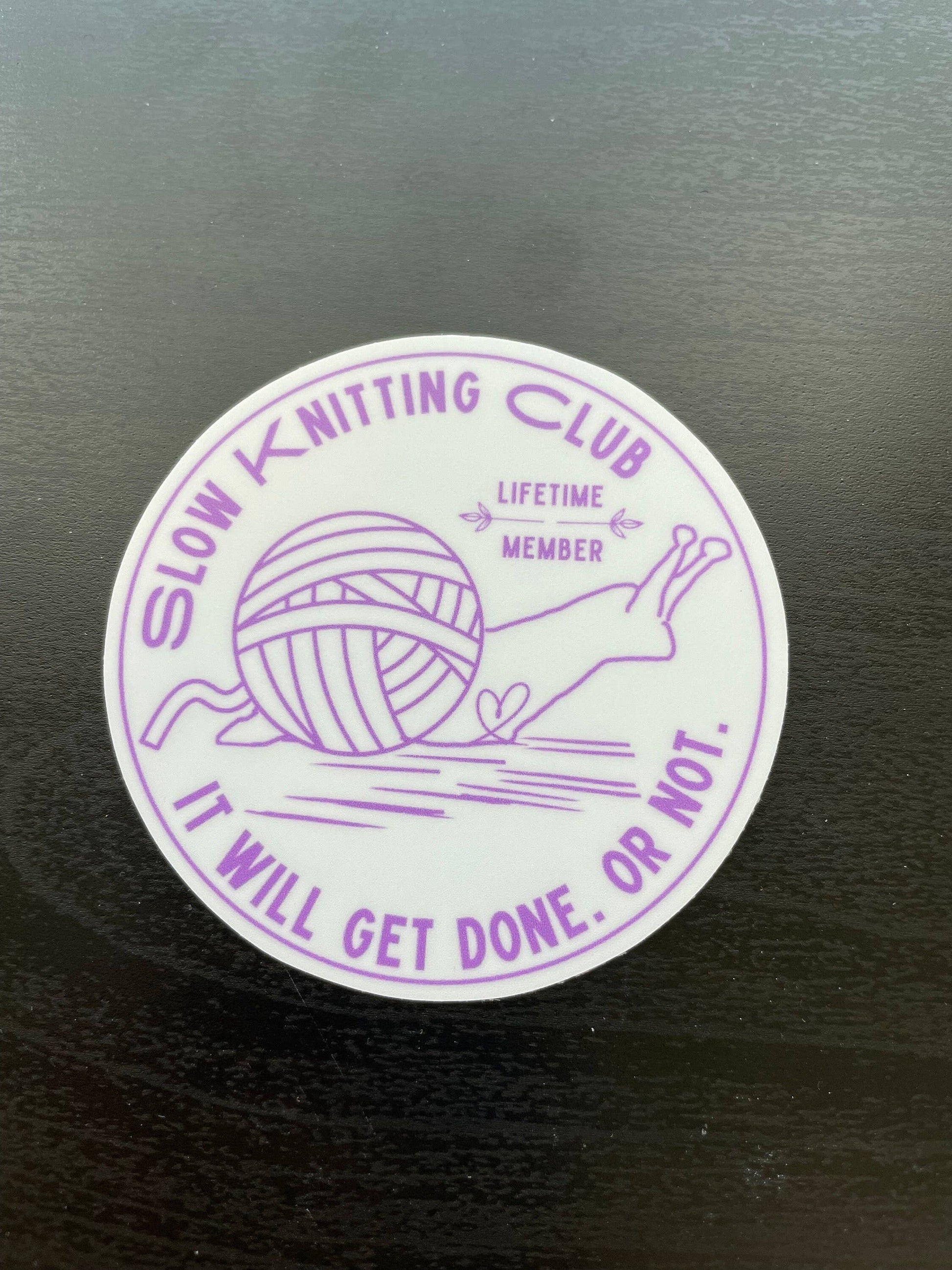 Purple 'Slow Knitting Club' sticker with a snail and yarn ball